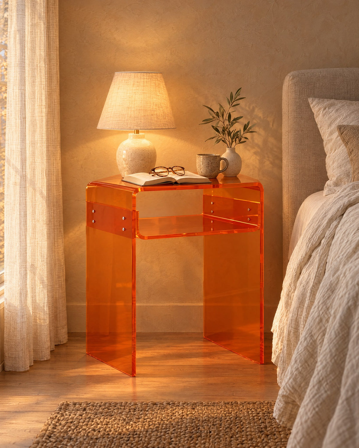 Amber acrylic bedside table, lamp switched on and an open book in the evening