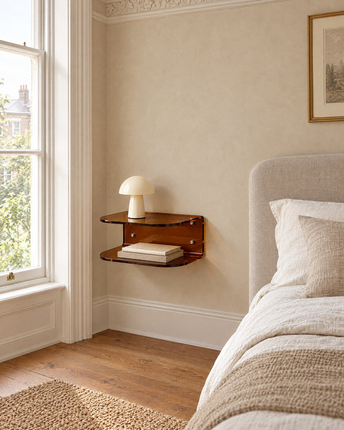 Amber acrylic floating bedside shelf beside a linen bed in a bright British bedroom with a sash window