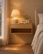 Bamboo floating bedside table with a lamp switched on and an open book in the evening