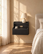 Black floating bedside table with a ceramic lamp in warm morning light