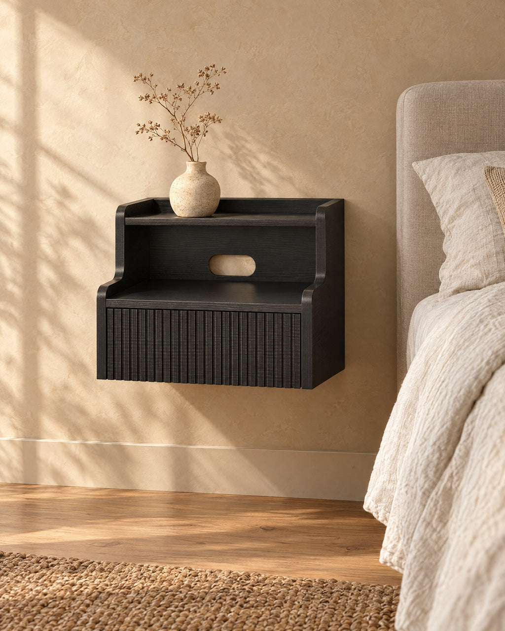 Three-quarter view of the black floating bedside table fixed to the wall above a clear floor