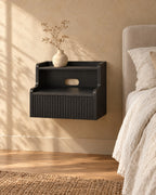 Three-quarter view of the black floating bedside table fixed to the wall above a clear floor
