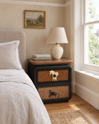 Black rattan bedside table with walnut top beside a linen bed in a British bedroom with a sash window