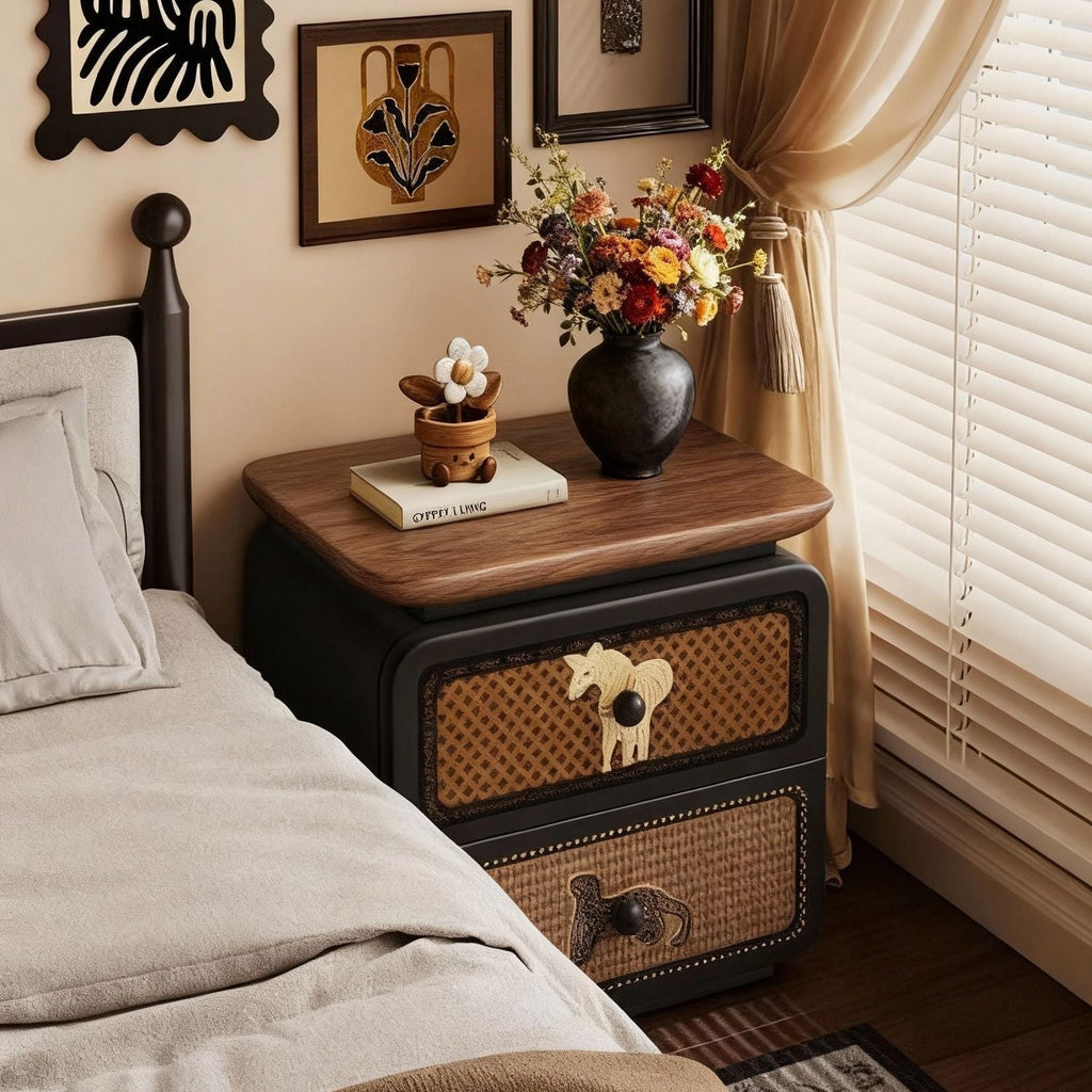 Black bedside table with rattan drawers and a walnut top beside a bed
