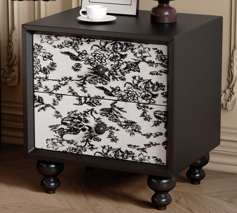 Black bedside table with floral toile drawers in a bedroom