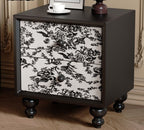 Black bedside table with floral toile drawers in a bedroom