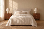 Pair of brown wood bedside tables with two drawers and brass pulls on each side of a double bed