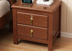 Brown wood bedside table with two drawers and brass pulls in a bedroom