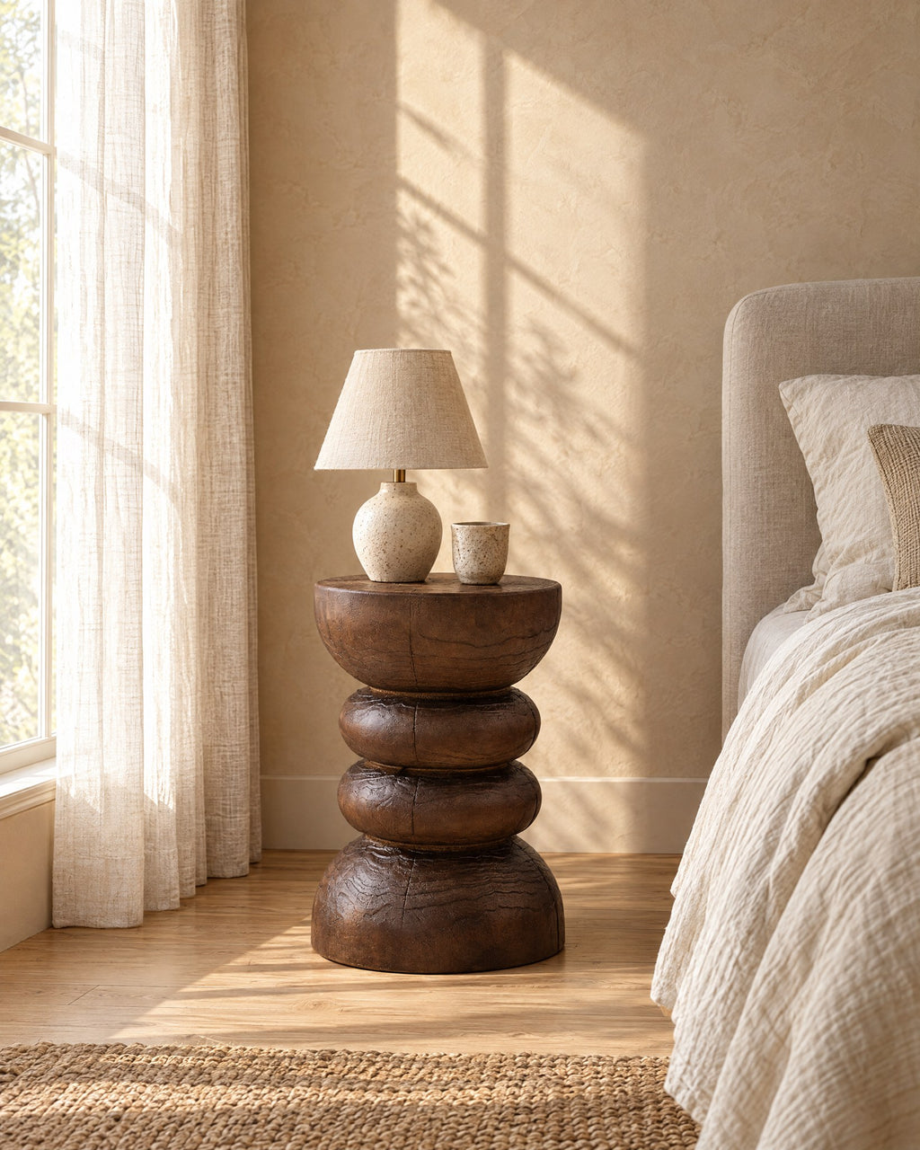 Carved wood pedestal bedside table in warm morning light