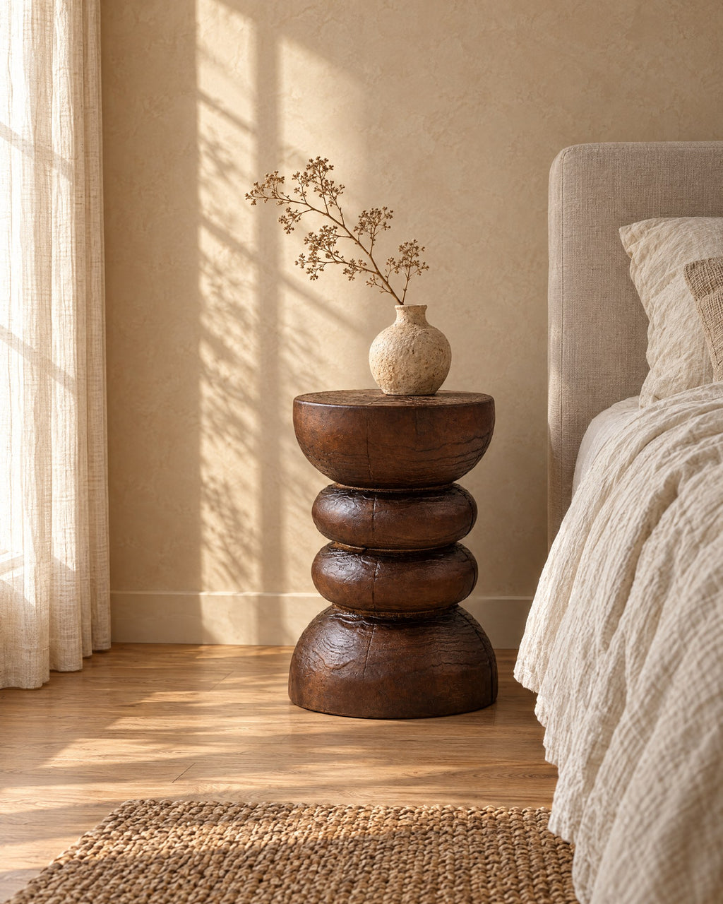 Three-quarter view of the carved wood pedestal bedside table