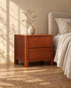 Three-quarter view of the cherry-tone wooden bedside table with two handle-free drawers