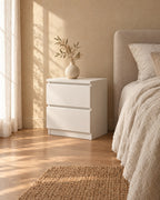 Three-quarter view of the compact white bedside table beside the bed