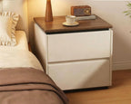 Cream bedside table with two drawers and a walnut-tone top beside a bed