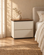 Three-quarter view of the cream bedside table showing its recessed base