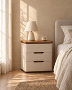 Cream bedside table with a walnut-tone top and a ceramic lamp in morning light