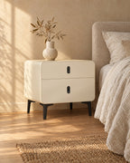 Three-quarter view of the cream bedside table with black metal legs