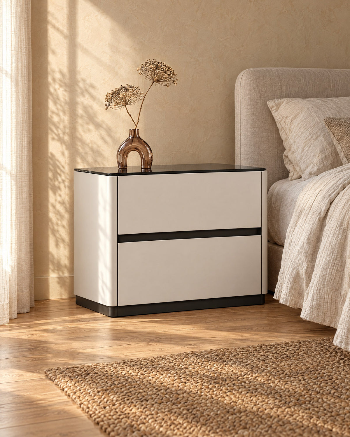 Three-quarter view of the cream bedside table with a glossy black top and two drawers