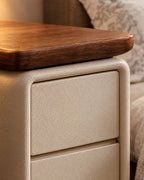 Close-up of the walnut-tone wooden top over the cream textured drawer front