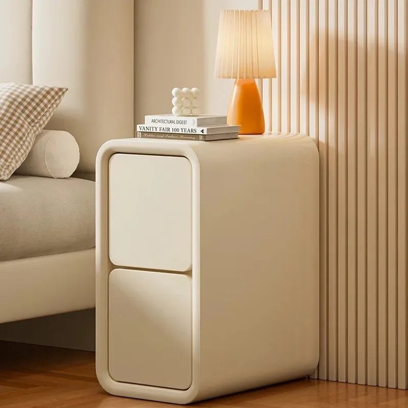 Cream leather-look bedside table with two handle-free drawers beside a bed