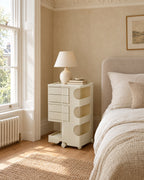 Cream rolling bedside trolley beside a linen bed in a British bedroom with a sash window