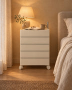 Cream rotating bedside storage unit with a lamp switched on and an open book in the evening