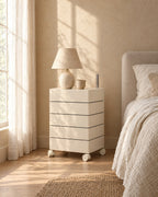 Cream five-tray bedside storage unit with a ceramic lamp in morning light