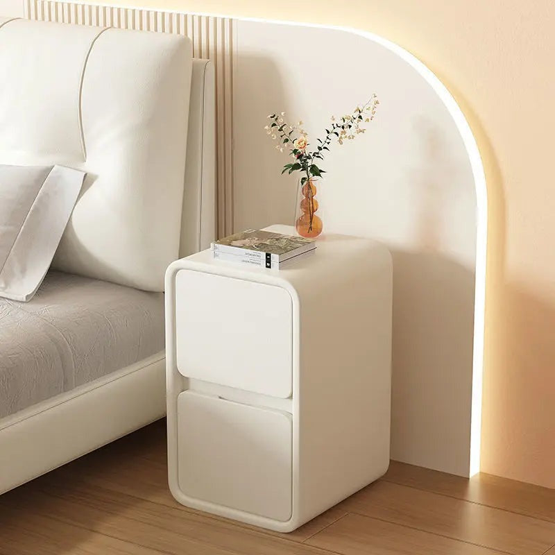 Cream rounded bedside table with two drawers beside a bed