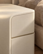 Close-up detail of the cream rounded bedside table with two handle-free drawers