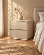 Cream rounded cube bedside table standing beside a bed with linen bedding
