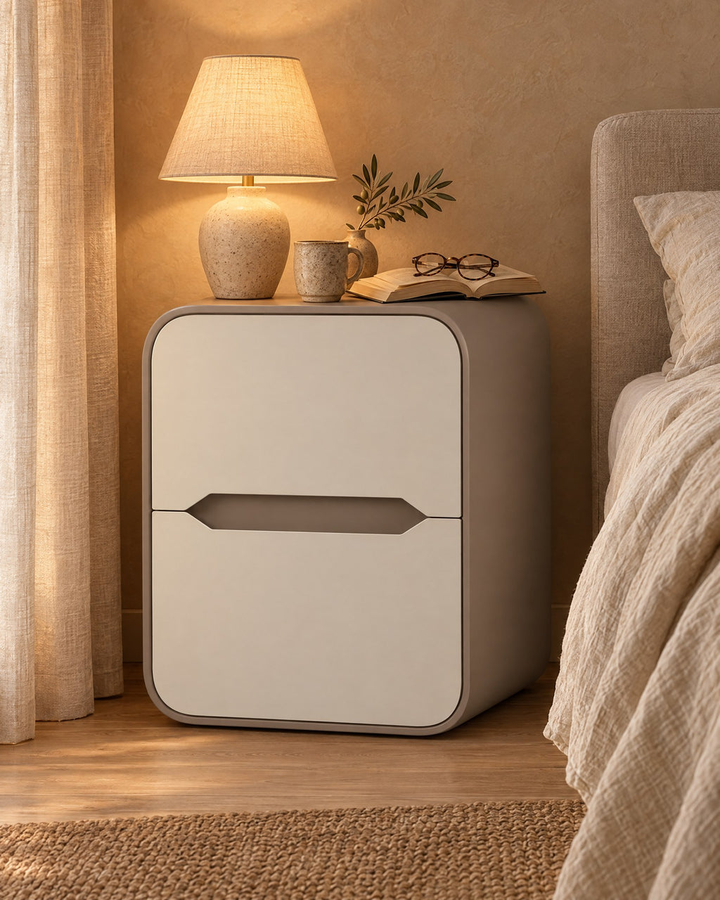 Cream and taupe rounded bedside table with a lamp switched on and an open book in the evening