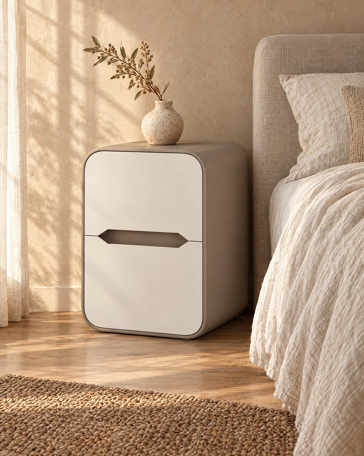Three-quarter view of the cream and taupe rounded bedside table