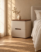 Three-quarter view of the cream bedside table showing the recessed walnut plinth