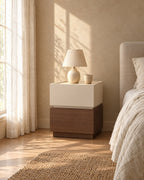 Two-tone cream and walnut bedside table with a ceramic lamp in morning light