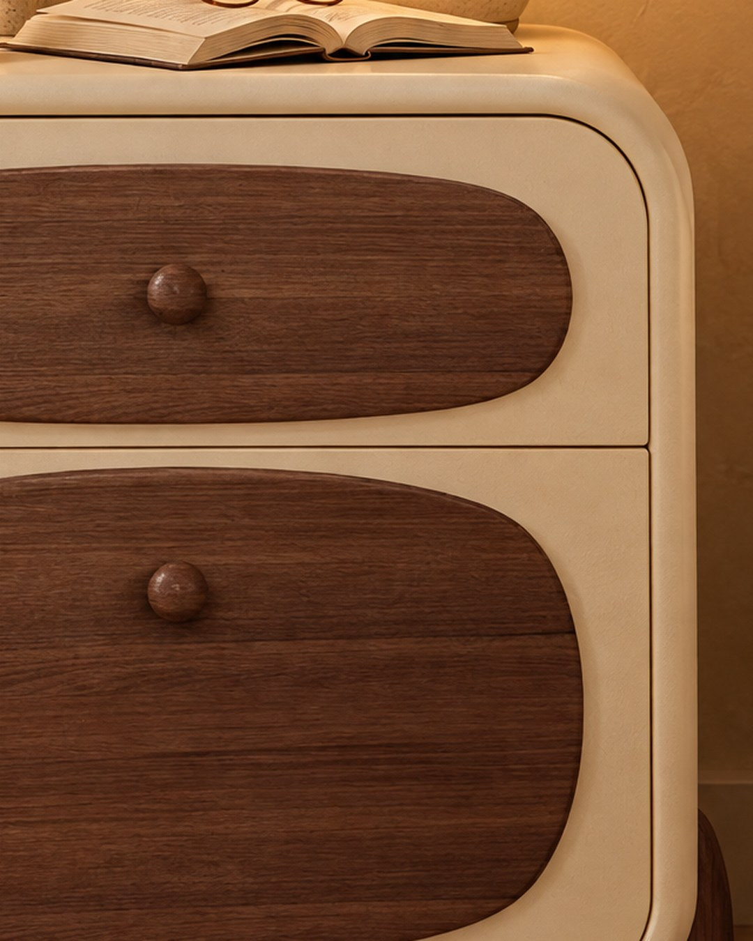 Close-up of the rounded walnut drawer front and its small round knob