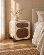 Three-quarter view of the cream bedside table showing its rounded walnut feet