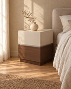 Three-quarter view of the two-tier bedside table showing the cream and walnut blocks and recessed plinth