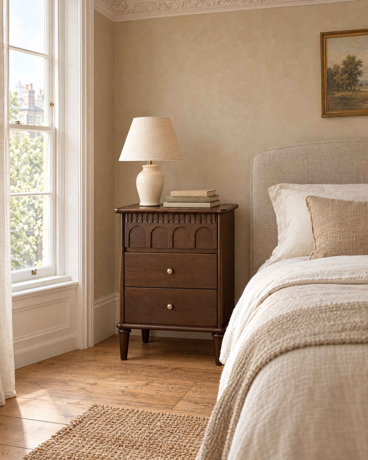 French-style walnut bedside table with three drawers in a British bedroom with a sash window