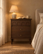 French-style dark walnut bedside table with a lamp switched on in the evening