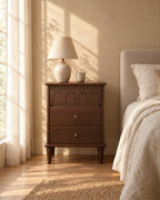 Dark walnut bedside table with carved arches in morning light