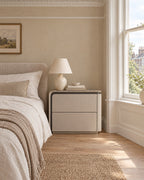 Greige two-drawer bedside table beside a linen bed in a British bedroom with a sash window