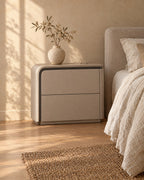 Three-quarter view of the greige bedside table showing its curved shell