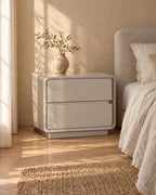 Three-quarter view of the greige lacquered bedside table showing its rounded frame