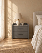 Grey bedside table with slim bar handles and a ceramic lamp in morning light