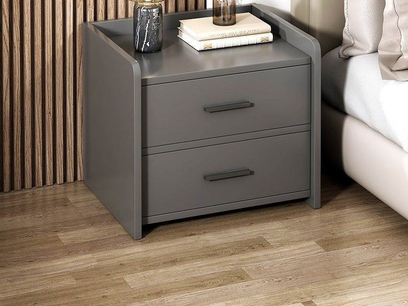 Grey bedside table with two drawers beside a bed