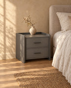 Three-quarter view of the grey bedside table showing its raised side panels