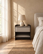 Grey stitched drawer bedside table with a ceramic lamp in morning light