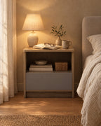 Grey oak bedside table with an open niche and grey drawer, lamp switched on in the evening