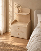 Three-quarter view of the light wood bedside table showing the raised rim and floating shelf