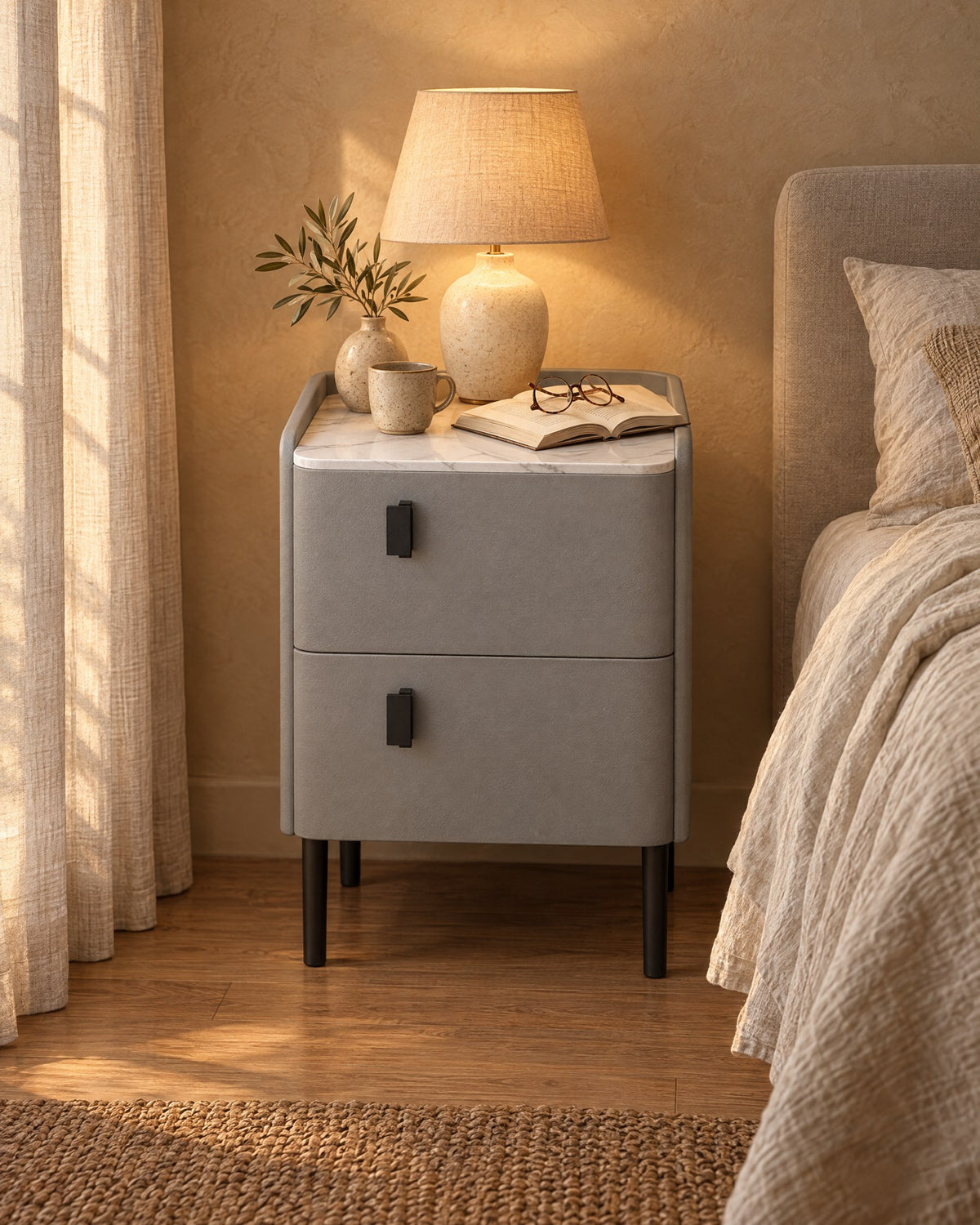 Narrow Grey Bedside Table with a lamp switched on and an open book in the evening