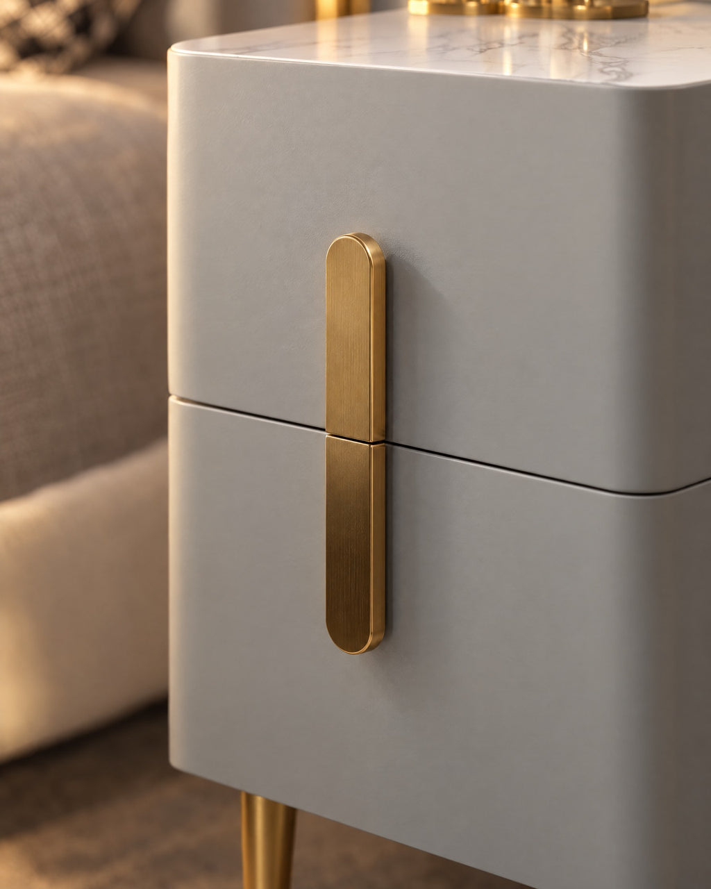 Close-up of the long gold bar handle across the two grey drawers
